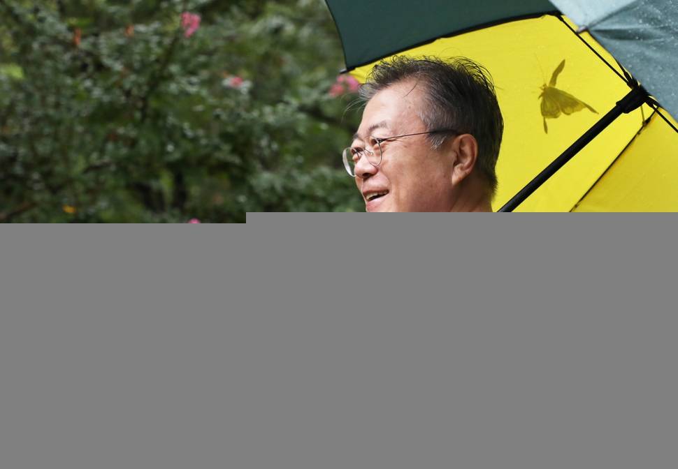 문재인 대통령이 29일 오전 경남 양산시 사저 뒷산에서 우산을 쓰고 산책하며 미소짓고 있다. 청와대 제공